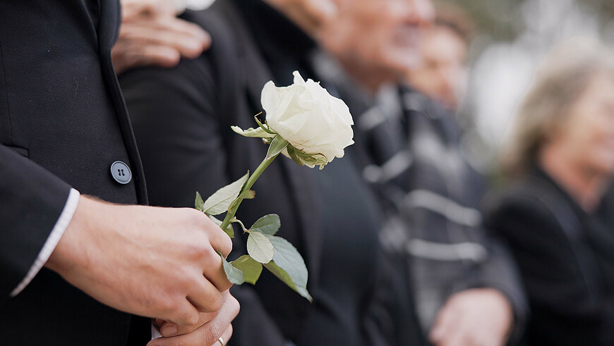 Mand holder hvid rose ved begravelse